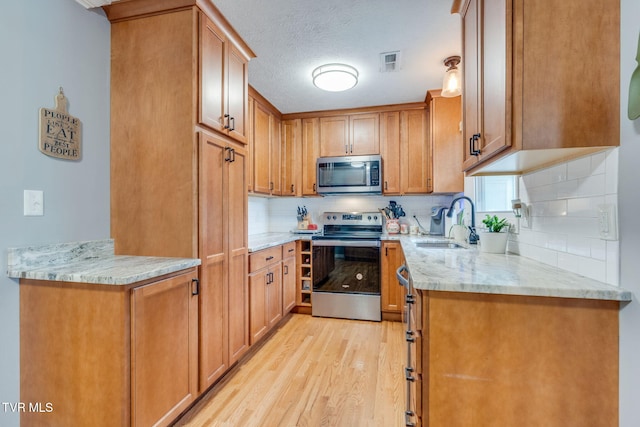 1933 Sand St, Kingsport, TN 37660 - kitchen with stainless steel appliances, light wood-type flooring, light stone counters, tasteful backsplash, and brown cabinets