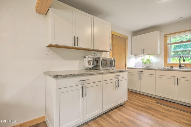 524 Boring Chapel Rd, Gray, TN 37615 - kitchen with white cabinetry, stainless steel microwave, light wood-style floors, and light stone countertops