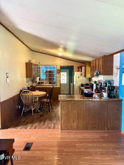 222 SW Azalea Dr, Wise, VA 24293 - kitchen with lofted ceiling, freestanding refrigerator, wood finished floors, brown cabinetry, and a peninsula
