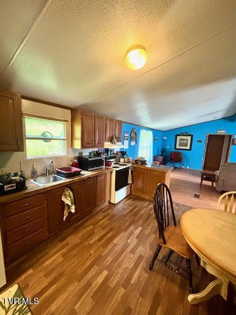 222 SW Azalea Dr, Wise, VA 24293 - kitchen with white electric stove, wood finished floors, a textured ceiling, stainless steel microwave, and vaulted ceiling