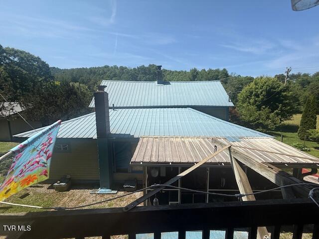 123 Mcmahan Gibbs Rd, Roan Mountain, TN 37687 - back of property with a metal roof, a chimney, and a wooded view