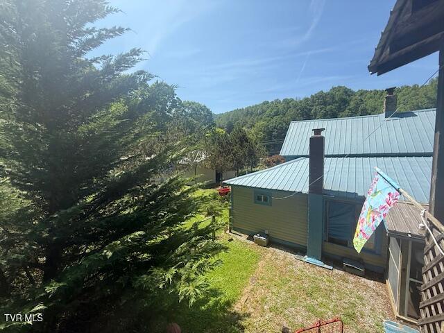 123 Mcmahan Gibbs Rd, Roan Mountain, TN 37687 - view of home's exterior with a chimney, a metal roof, a forest view, and a standing seam roof