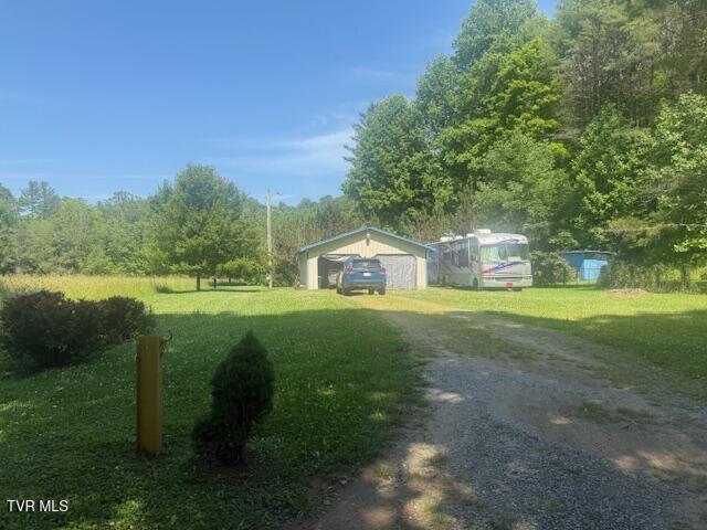 123 Mcmahan Gibbs Rd, Roan Mountain, TN 37687 - view of green lawn featuring driveway, a wooded view, and a detached garage