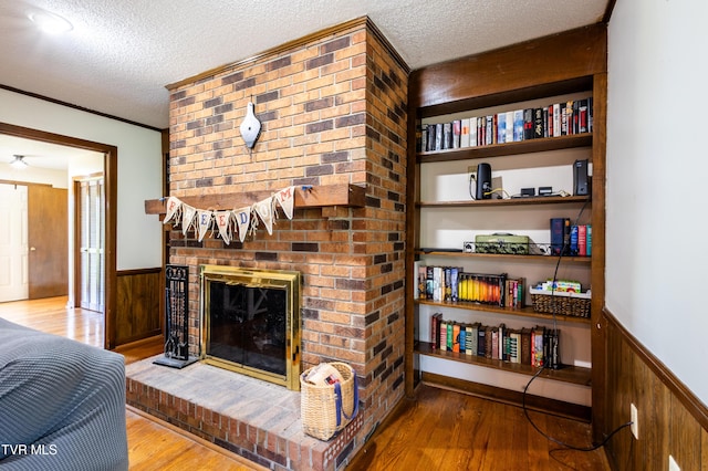 274 Hickam Orchard Rd, Kingsport, TN 37660 - living room featuring a wainscoted wall, wood finished floors, a textured ceiling, wood walls, and a brick fireplace