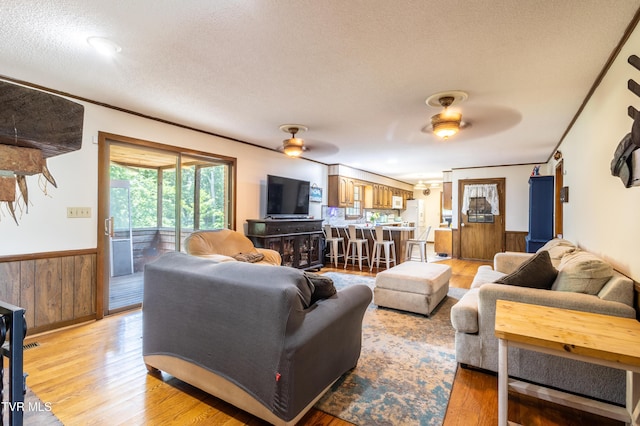 274 Hickam Orchard Rd, Kingsport, TN 37660 - living room featuring a ceiling fan, wainscoting, a textured ceiling, light wood finished floors, and wood walls