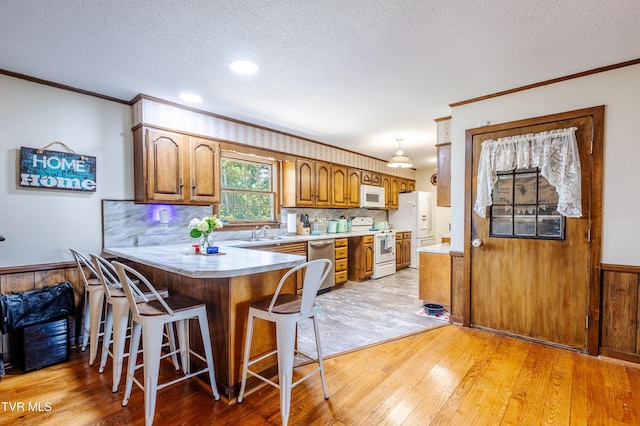274 Hickam Orchard Rd, Kingsport, TN 37660 - kitchen with white appliances, crown molding, a peninsula, light wood-style floors, and brown cabinetry