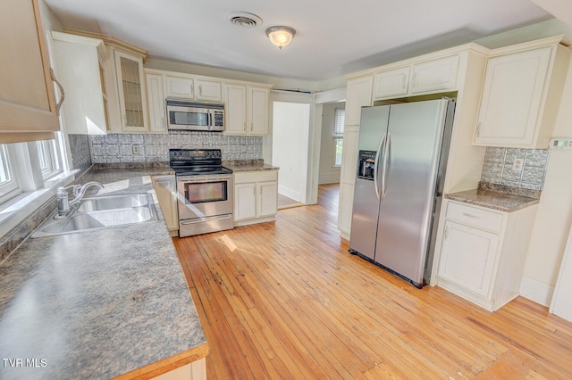 1330 Carroll Creek Rd, Gray, TN 37615 - kitchen with appliances with stainless steel finishes, decorative backsplash, light wood-style floors, and glass insert cabinets