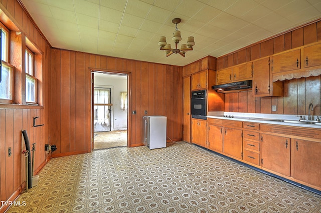 325 Cove Creek Rd, Roan Mountain, TN 37687 - kitchen featuring black appliances, under cabinet range hood, brown cabinets, wood walls, and light countertops