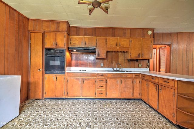 325 Cove Creek Rd, Roan Mountain, TN 37687 - kitchen with black oven, under cabinet range hood, wooden walls, light countertops, and ceiling fan