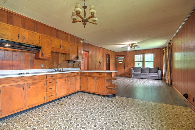 325 Cove Creek Rd, Roan Mountain, TN 37687 - kitchen featuring under cabinet range hood, wooden walls, a chandelier, brown cabinets, and light countertops