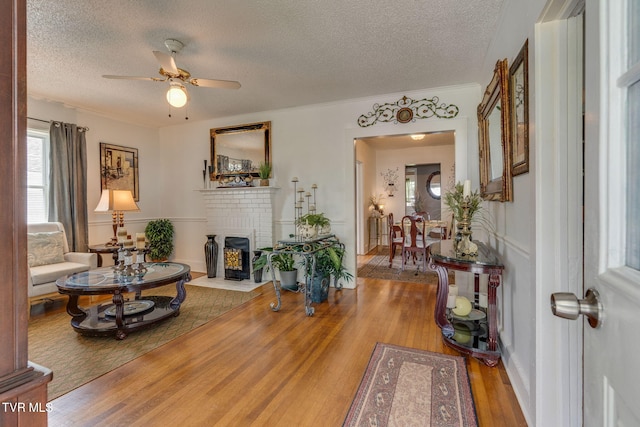 1634 Highland St, Kingsport, TN 37664 - living room featuring a textured ceiling, a ceiling fan, wood finished floors, and a brick fireplace