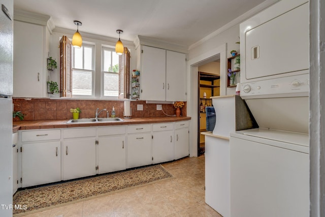1634 Highland St, Kingsport, TN 37664 - kitchen with stacked washing machine and dryer, backsplash, ornamental molding, white cabinetry, and tile countertops