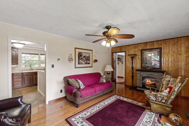 126 Poplar Hill Dr, Johnson City, TN 37604 - living room featuring a ceiling fan, wood walls, a fireplace, crown molding, and light wood-style flooring