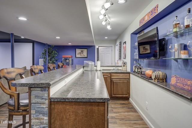 305 Emerald Chase Cir, Johnson City, TN 37615 - kitchen featuring dark countertops, dark wood finished floors, a breakfast bar, a peninsula, and brown cabinetry