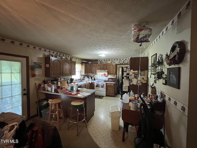 3911 Tate Springs Rd, Big Stone Gap, VA 24219 - kitchen with white range, a textured ceiling, a peninsula, under cabinet range hood, and a breakfast bar