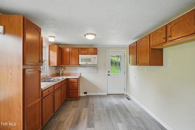 271 Anderson St, Pennington Gap, VA 24277 - kitchen with white microwave, wood finished floors, brown cabinets, a textured ceiling, and light countertops