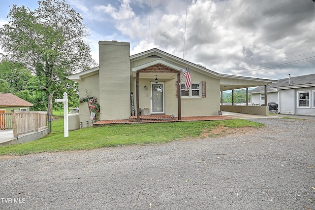 53 Grove Ave, Lebanon, VA 24266 - view of front of home with gravel driveway, a chimney, brick siding, and a carport