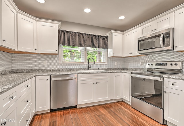 53 Grove Ave, Lebanon, VA 24266 - kitchen featuring appliances with stainless steel finishes, white cabinets, light wood-type flooring, tasteful backsplash, and recessed lighting