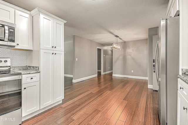 53 Grove Ave, Lebanon, VA 24266 - kitchen with appliances with stainless steel finishes, white cabinetry, wood finished floors, backsplash, and light stone counters