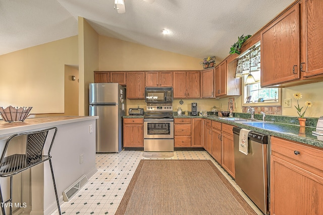 103 Jenny Ln, Jonesborough, TN 37659 - kitchen featuring appliances with stainless steel finishes, vaulted ceiling, dark countertops, brown cabinetry, and light flooring