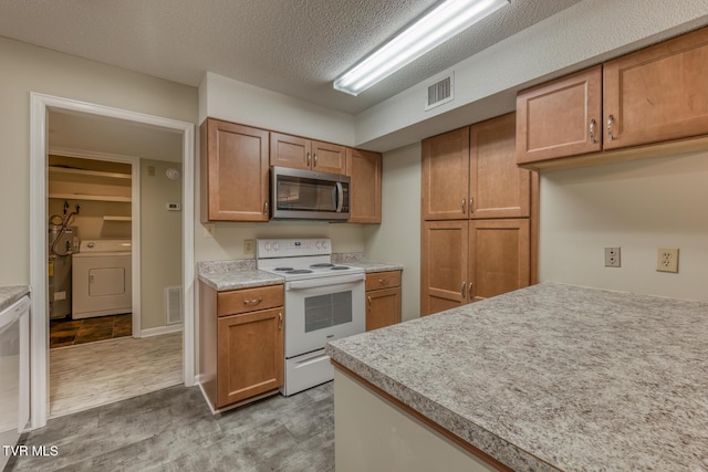 202 University Pkwy Unit 4E, Johnson City, TN 37604 - kitchen featuring stainless steel microwave, electric range, washer / clothes dryer, light countertops, and brown cabinetry