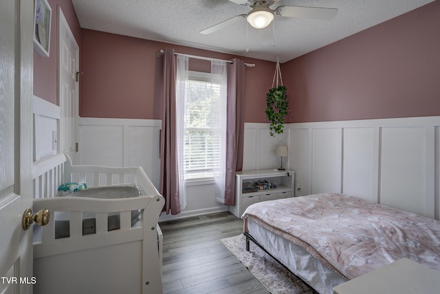 33 Mockingbird Ct, Jonesborough, TN 37659 - bedroom featuring a textured ceiling, a decorative wall, wainscoting, light wood-type flooring, and a ceiling fan