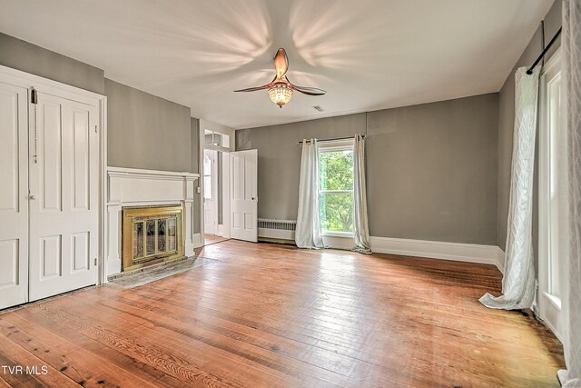 2061 King College Rd, Bristol, TN 37620 - unfurnished living room featuring radiator, a ceiling fan, a fireplace with flush hearth, and hardwood / wood-style flooring