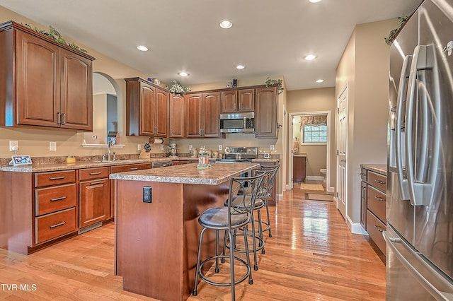 5000 Aberlea Pl, Piney Flats, TN 37686 - kitchen with stainless steel appliances, a kitchen breakfast bar, a kitchen island, arched walkways, and light wood-style flooring