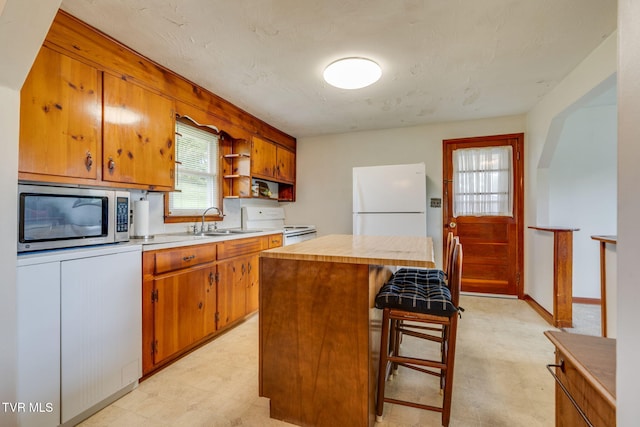 221 Mcfarland Dr, Kingsport, TN 37664 - kitchen featuring white appliances, light countertops, a center island, and brown cabinetry