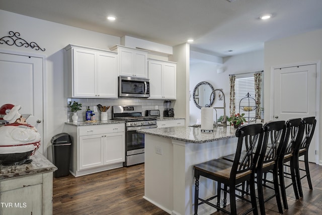 194 Wanderlust Ct, Johnson City, TN 37604 - kitchen featuring stainless steel appliances, light stone countertops, backsplash, dark wood-style flooring, and a center island with sink