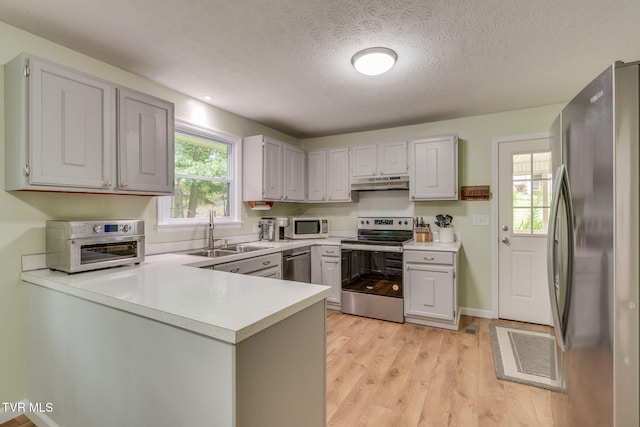 380 Lovelace Loop, Mountain View Loop, Fall Branch, TN 37656 - kitchen with appliances with stainless steel finishes, under cabinet range hood, a peninsula, light countertops, and a textured ceiling