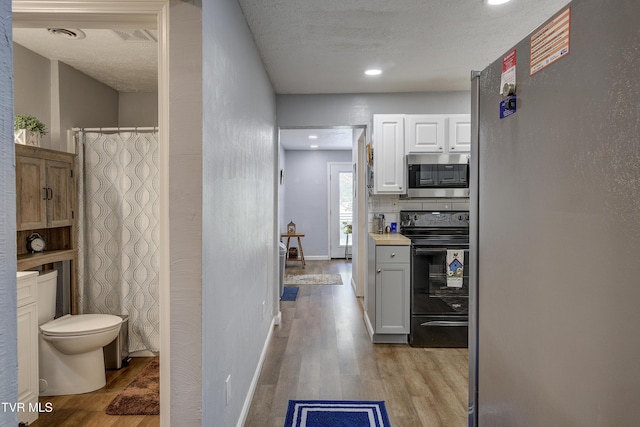 1277 Cooks Valley Rd, Kingsport, TN 37664 - kitchen with stainless steel appliances, light wood finished floors, light countertops, a textured ceiling, and white cabinetry
