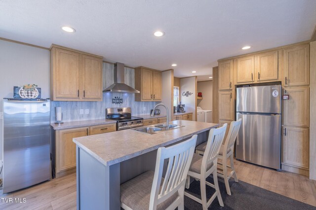 120 Maple Crest Cir, Surgoinsville, TN 37873 - kitchen with stainless steel appliances, wall chimney exhaust hood, washer and dryer, light wood finished floors, and light countertops