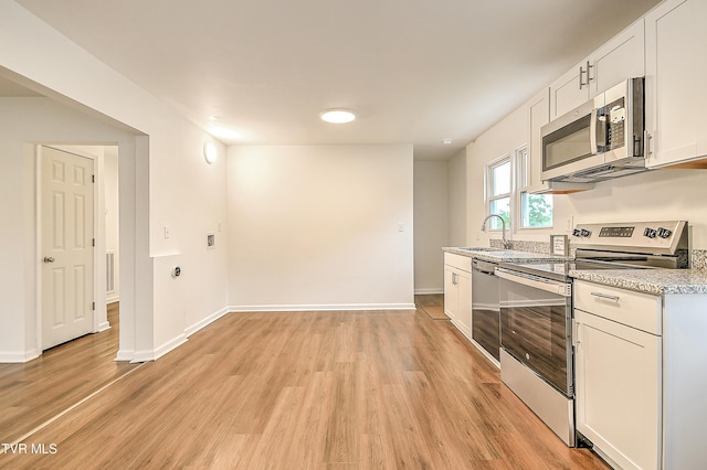 1648 E St, Kingsport, TN 37664 - kitchen featuring stainless steel appliances, light wood-style floors, white cabinetry, and light stone countertops