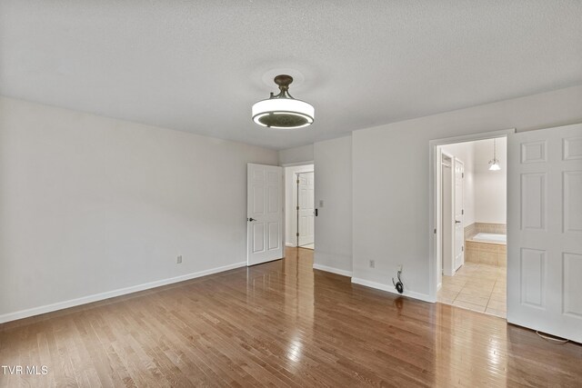 945 Dashaway Rd, Chuckey, TN 37641 - unfurnished bedroom featuring wood finished floors, a textured ceiling, and ensuite bath
