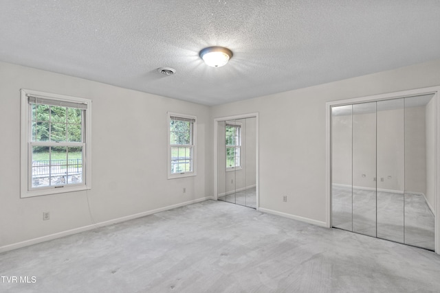 945 Dashaway Rd, Chuckey, TN 37641 - unfurnished bedroom featuring two closets, multiple windows, carpet floors, and a textured ceiling