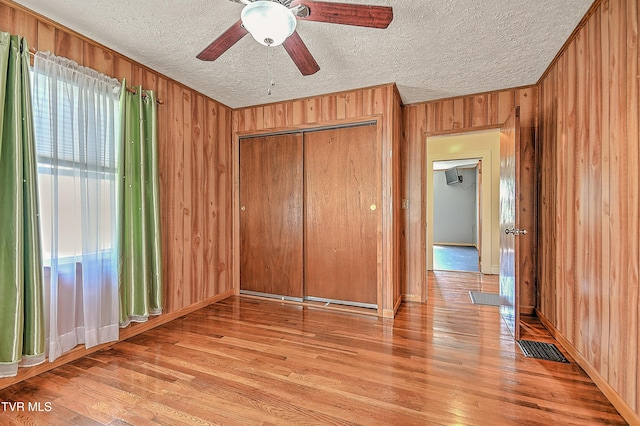 307 Tween Hills Rd, Bristol, TN 37620 - unfurnished bedroom with wooden walls, light wood-style floors, a textured ceiling, a closet, and ceiling fan