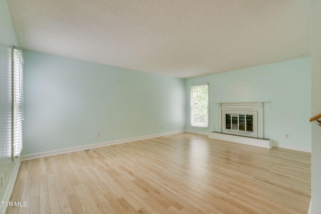 256 S Creek Ct, Kingsport, TN 37663 - unfurnished living room featuring light wood-style flooring, a textured ceiling, and a glass covered fireplace