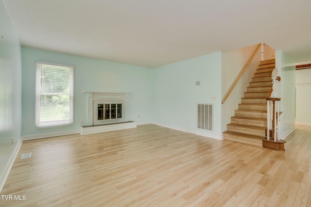 256 S Creek Ct, Kingsport, TN 37663 - unfurnished living room with light wood-style flooring, stairway, and a glass covered fireplace