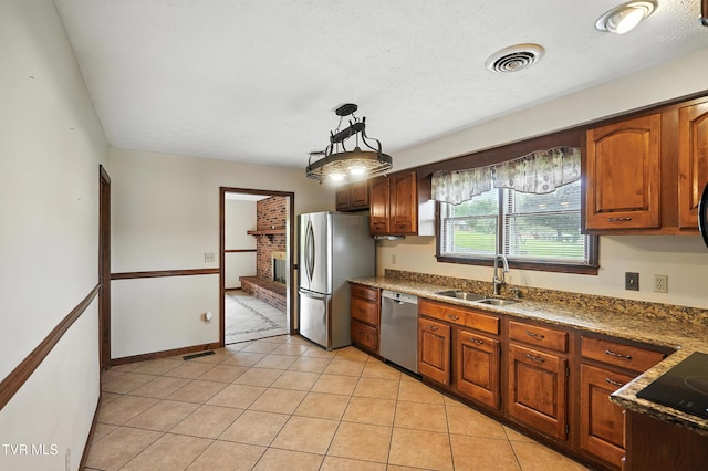 134 Richmond Hts, Jonesville, VA 24263 - kitchen featuring stainless steel appliances, light tile patterned floors, hanging light fixtures, a brick fireplace, and brown cabinets