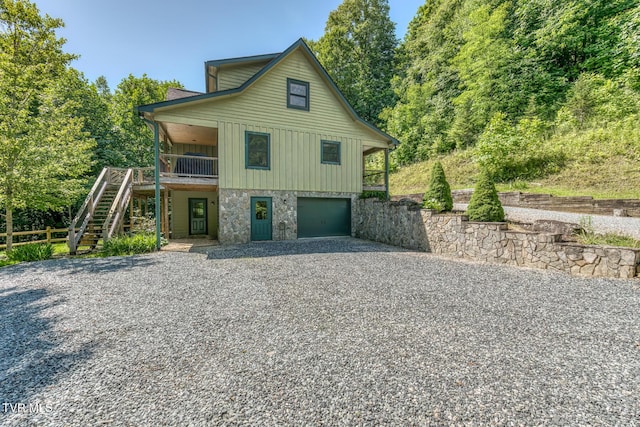 410 Eagle Ridge Rd, Roan Mountain, TN 37687 - view of front of house with board and batten siding, stairs, gravel driveway, an attached garage, and stone siding