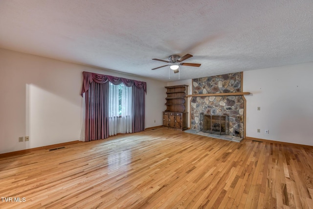 15060 Peaceful Valley Rd, Abingdon, VA 24210 - unfurnished living room featuring a ceiling fan, hardwood / wood-style flooring, a stone fireplace, and a textured ceiling