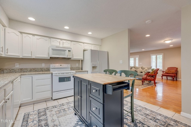 19275 Wyndale Rd, Abingdon, VA 24210 - kitchen featuring white appliances, white cabinets, a kitchen breakfast bar, light tile patterned floors, and recessed lighting