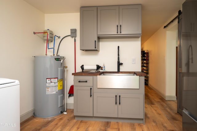 101 Ridgewood Dr, Bristol, TN 37620 - kitchen with electric water heater, gray cabinets, washer / clothes dryer, light wood-style floors, and a barn door