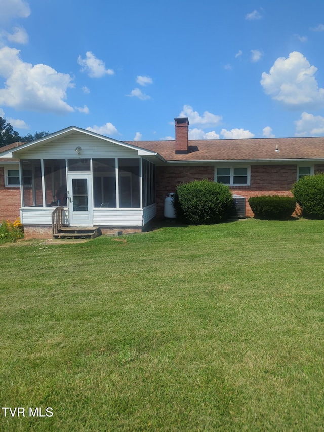 233 Pioneer Haven Ln, Kingsport, TN 37663 - back of property with a sunroom, a chimney, a lawn, and brick siding