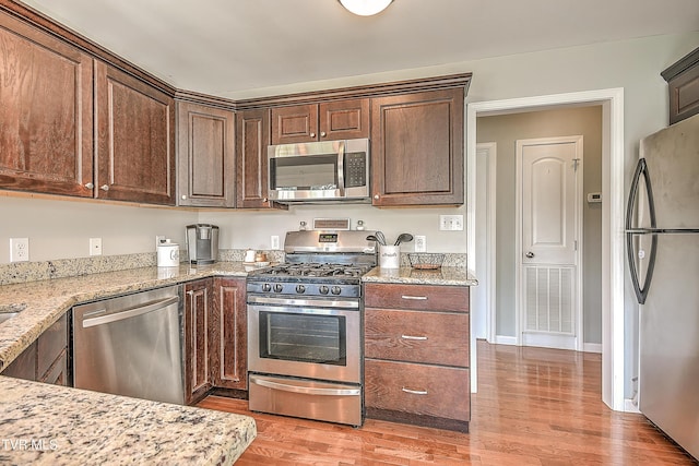 517 W Glade St, Glade Spring, VA 24340 - kitchen featuring appliances with stainless steel finishes, light wood-style flooring, light stone counters, and dark brown cabinets