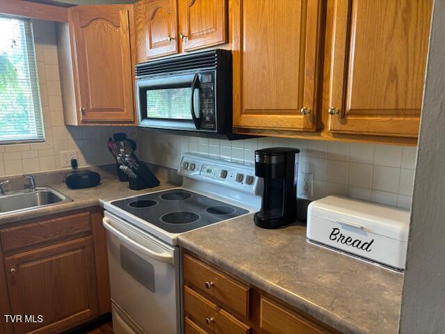 1145 Carriage Cir Unit 204, Bristol, VA 24201 - kitchen with white range with electric cooktop, black microwave, tasteful backsplash, and brown cabinetry
