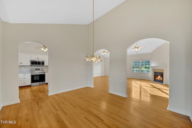 114 Wiltshire Dr, Gray, TN 37615 - unfurnished living room featuring ceiling fan, arched walkways, light wood-style floors, a fireplace with flush hearth, and high vaulted ceiling