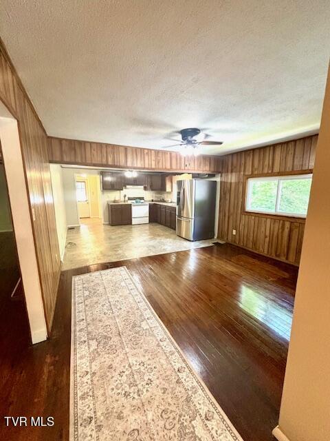 3219 Hardy Hollow Rd, Saint Paul, VA 24283 - unfurnished living room featuring wooden walls, dark wood finished floors, a ceiling fan, and a textured ceiling
