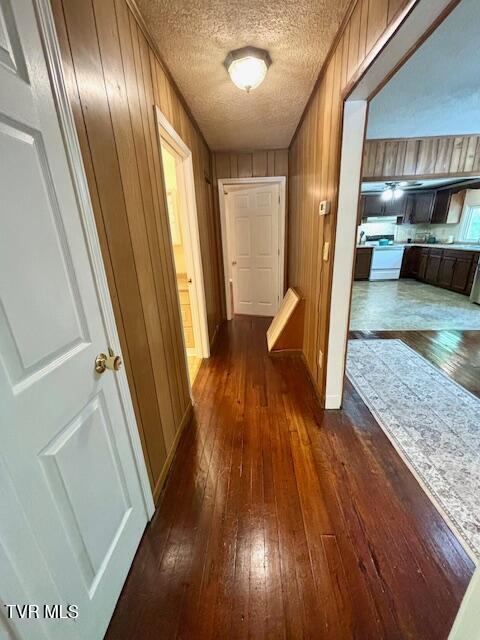 3219 Hardy Hollow Rd, Saint Paul, VA 24283 - hall with dark wood-style floors, wooden walls, and a textured ceiling